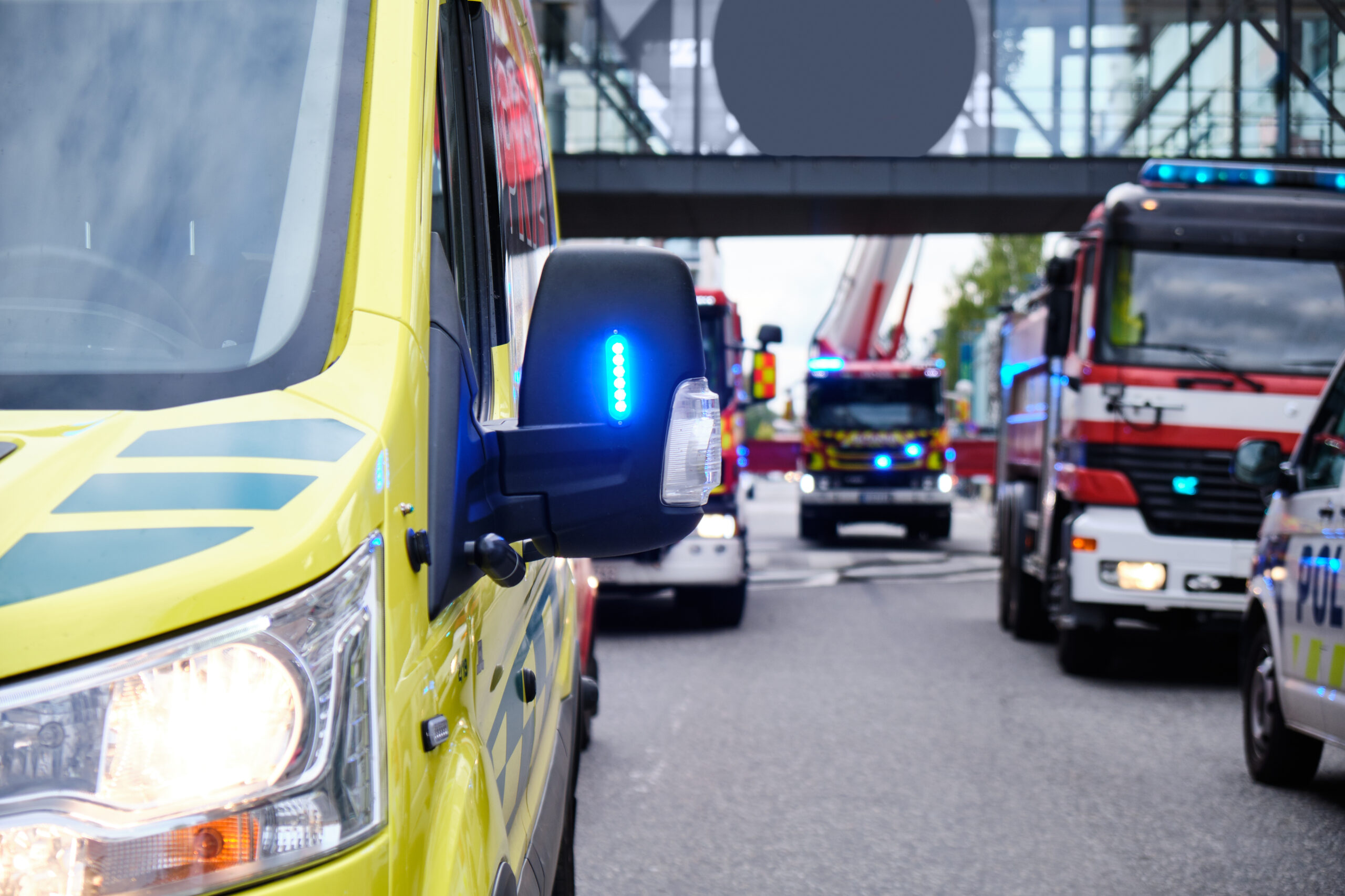 Emergency services vehicles including an ambulance and fire engines responding on a city street, representing frontline professionals supported by Temple Legal Protection’s insurance products