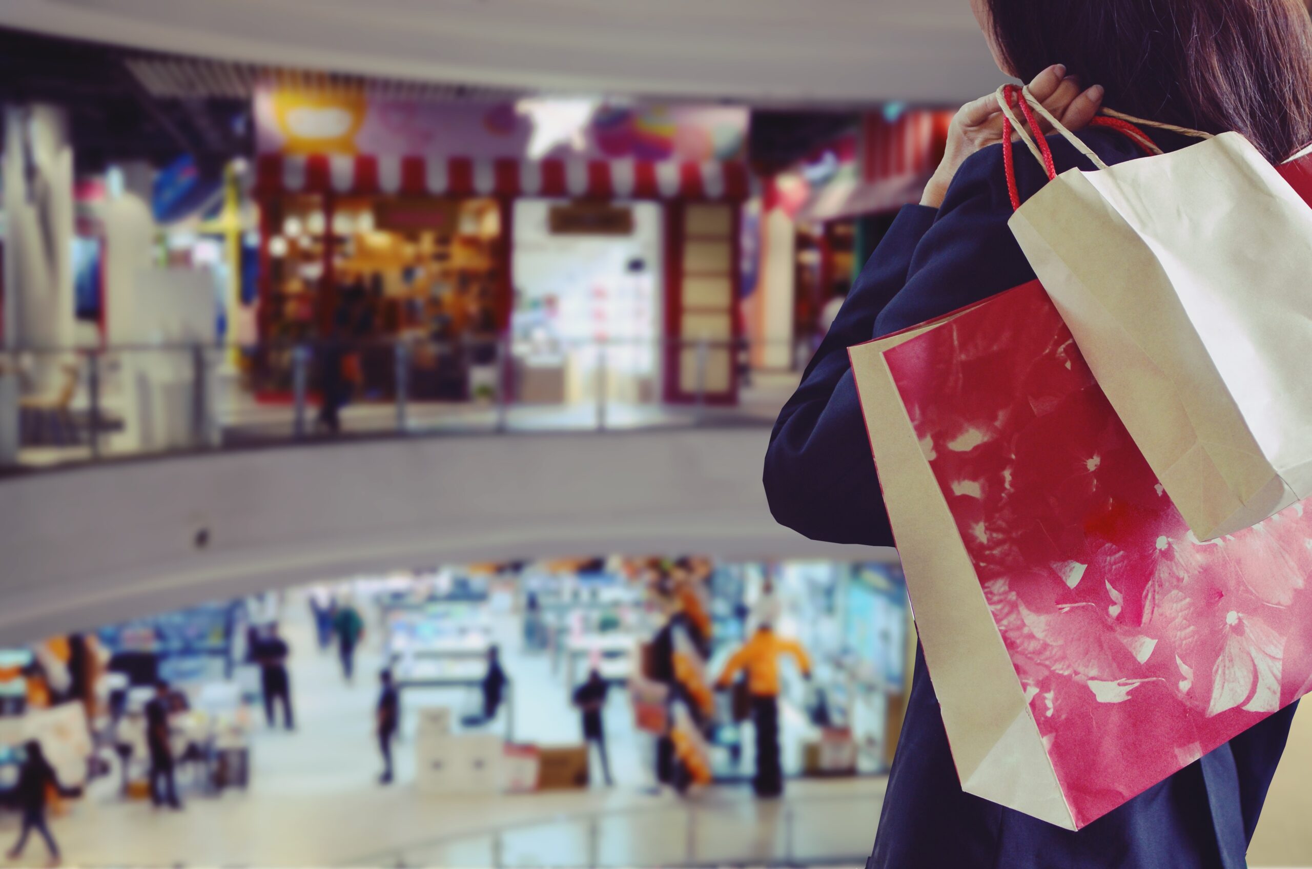 Shopper carrying retail shopping bags in a busy shopping centre, representing retail environments supported by Temple Legal Protection’s commercial legal expenses insurance.